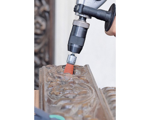 Borrmaskin med borsttillsats rengör en träprydnad