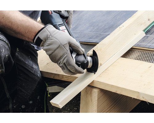 En person skär en träplanka med ett multifunktionsverktyg.