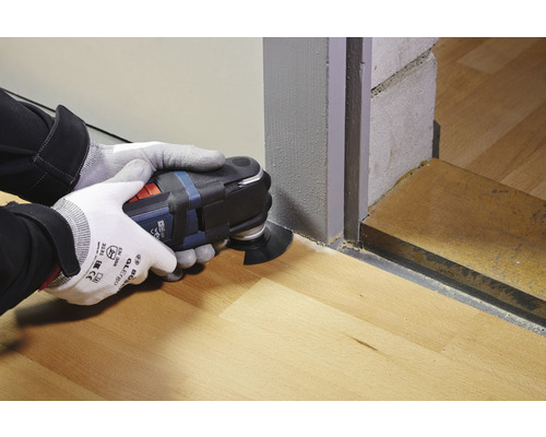 Operatör använder multifunktionsverktyg för att såga på trägolv