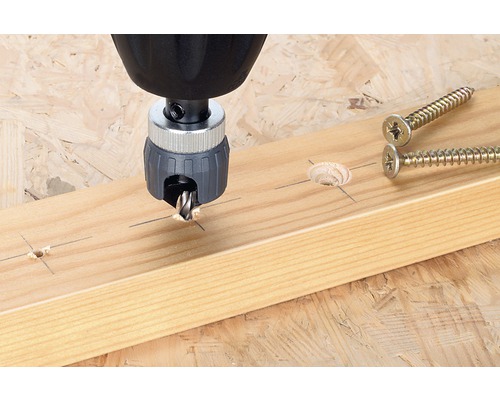 Försänkare i drift på en träplanka bredvid skruvar