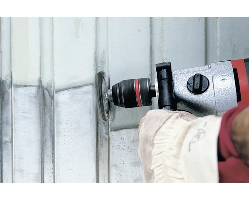 Person använder en borrmaskin med stålborste för att rengöra en metallyta