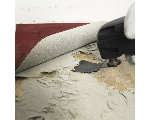 Oscillerande multiverktyg som tar bort limrester från ett trägolv