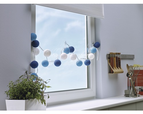 Dekorativt fönster med ljusslinga, persienn och krukväxt på fönsterbrädan