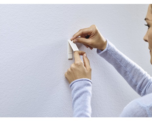 Kvinna fäster en självhäftande krok på väggen