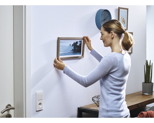 Kvinna hänger inramad bild på väggen i vardagsrummet