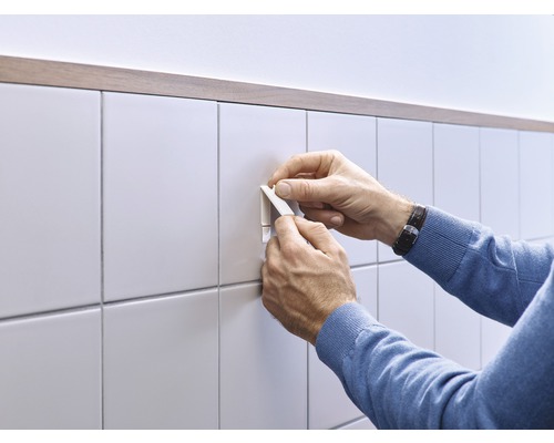 Man fäster kakelskena på väggkakel