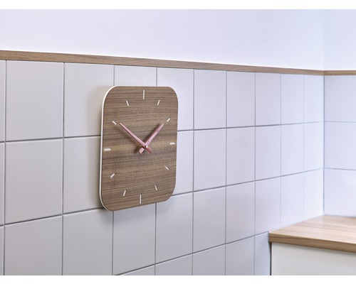 Träväggklocka med rosa visare på väggen