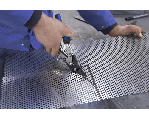 En person skär perforerad plåt med en plåtsax.