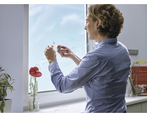 Kvinna fäster fönstertätning på fönsterkarmen