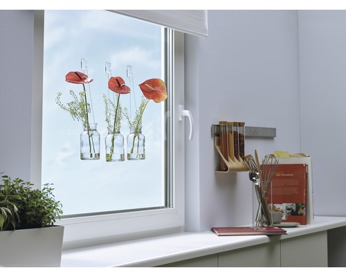 Tre vaser med blommor hänger på ett fönster i ett ljust rum.