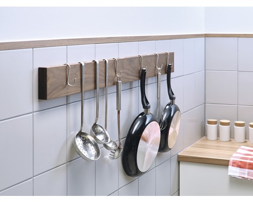 Köksredskap hänger på en köksstång på väggen.