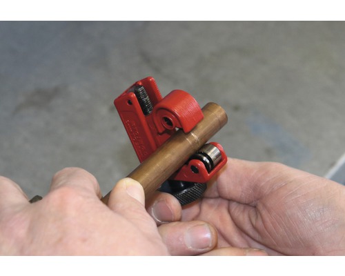 En kopparrörskärare skär ett kopparrör.