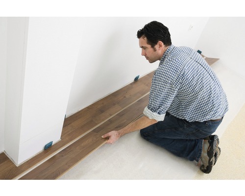 Man lägger laminatgolv inomhus med distanser.