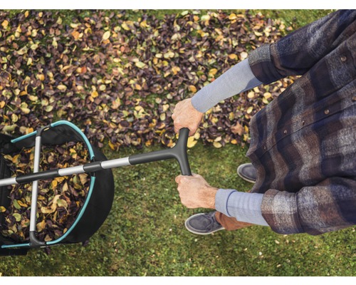Översikt av en person med en lövsamlare på en gräsmatta med höstlöv