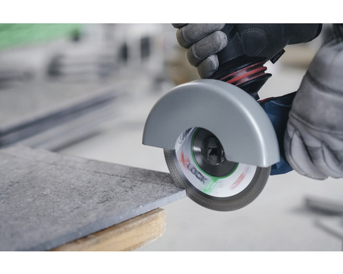 En person skär en kakelplatta med en vinkelslip