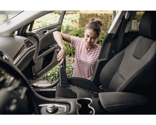 Kvinna dammsuger bilsäten med dammsugare