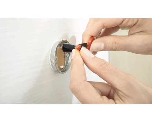 En person som sätter in en elektrisk ledare i en vägganslutningsdosa