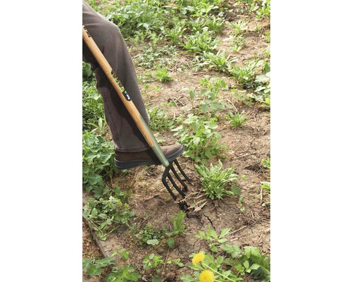 Person använder en grep för trädgårdsarbete.