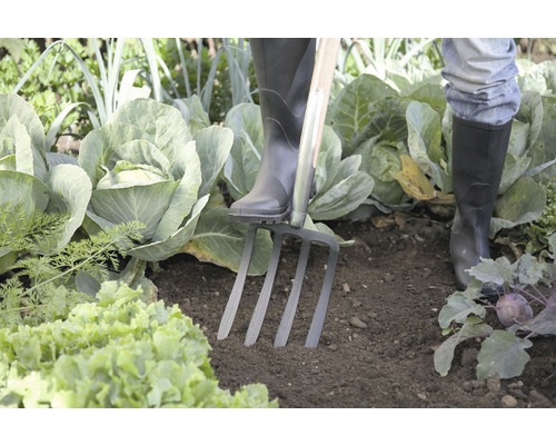 Person med stövlar och spade i grönsaksträdgården