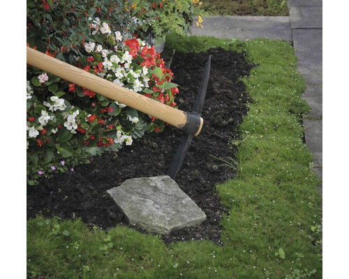 Trädgårdsscen med en hacka, blommor och gräs