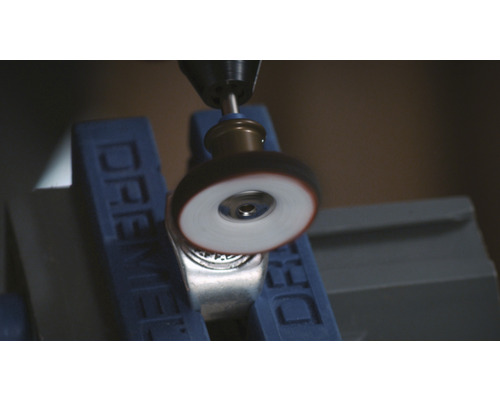 Dremel-verktyg polerar en metallring i ett skruvstäd