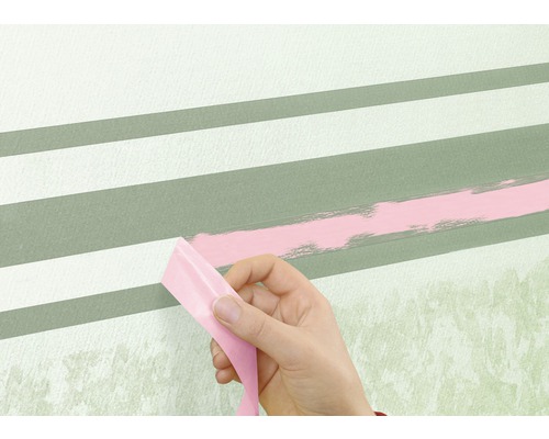 Hand tar bort maskeringstejp från en vägg med ränder