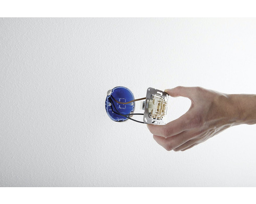 Hand monterar en strömbrytare i en väggdosa.