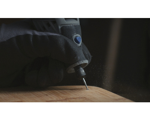 Hand med skyddshandske använder en multifunktionsslipmaskin på en träplanka.