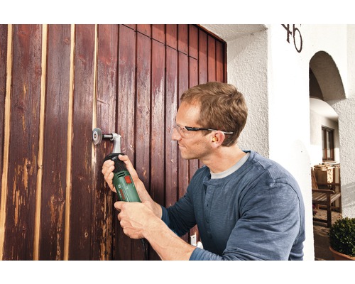 Man arbetar med en multislipmaskin på en trädörr.