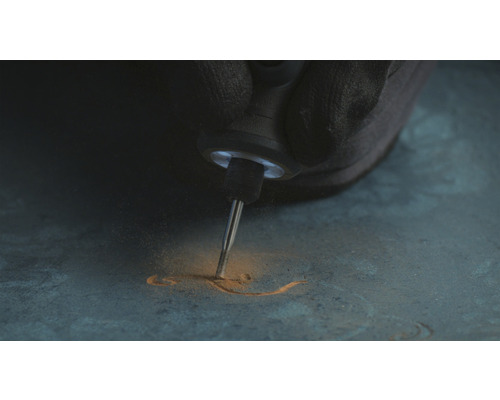 En person graverar med ett multifunktionsverktyg i ett material.