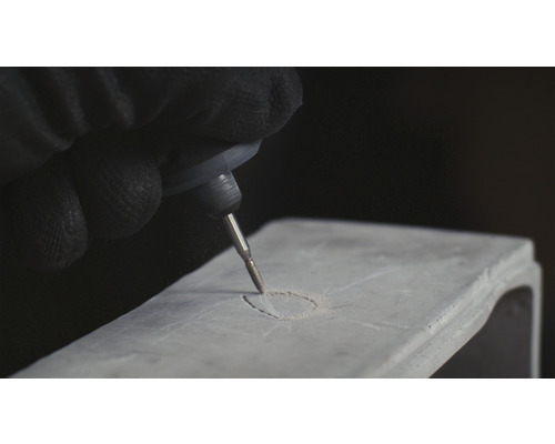 En person graverar ett föremål med en gravyrverktyg.