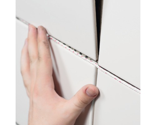 En person fogar vita plattor med en fogsnöre.