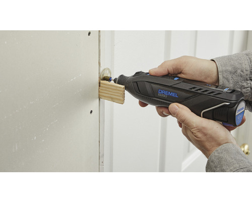 En person använder ett Dremel multiverktyg för att slipa trä.