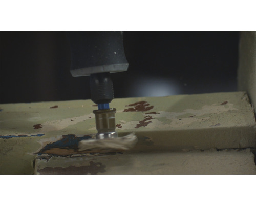 En borr slipar färg från en fönsterkarm.