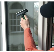 Person rengör fönster med en fönsterskrapa