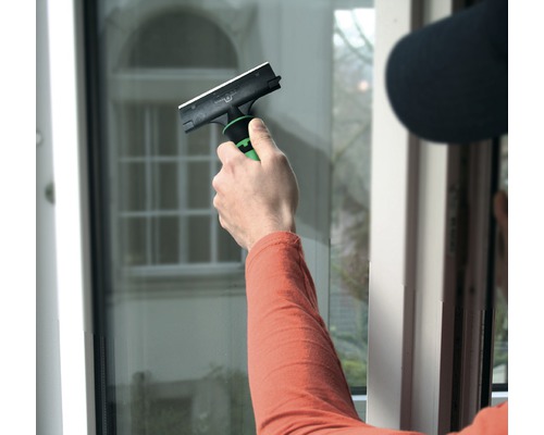 Person rengör fönster med en fönsterskrapa