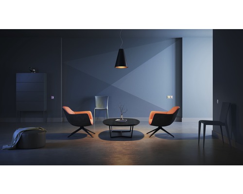 Vardagsrum med två fåtöljer, ett soffbord, en hängande lampa och en skänk