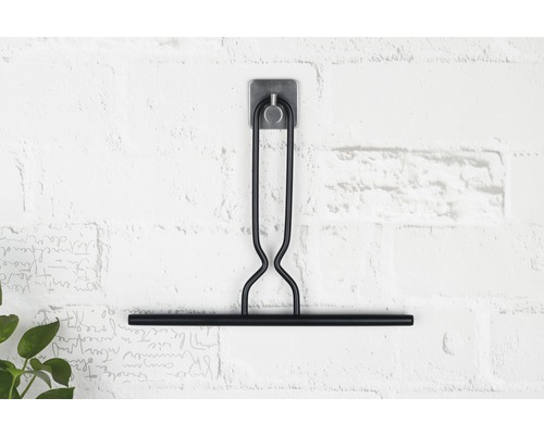 Svart badrumsskrapa med hållare på en vägg