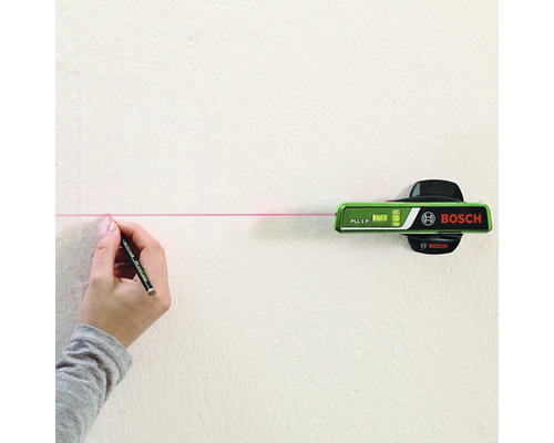 Bosch logotyp. En person markerar en linje med blyertspenna och laservattenpass på väggen.
