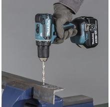 Makita sladdlös skruvdragare som borrar genom en metallbit som sitter fast i ett skruvstäd.