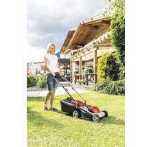 Kvinna använder gräsklippare i trädgården