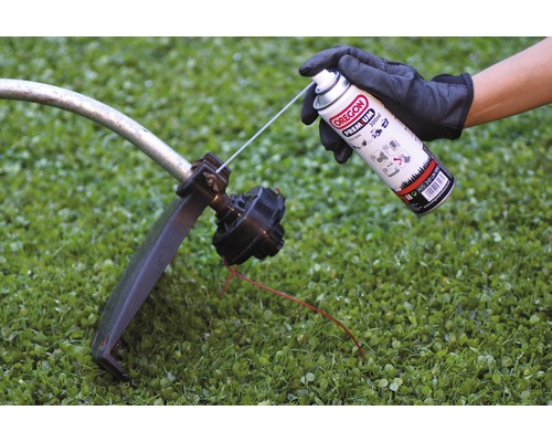En hand sprayar Oregon Premium 300 milliliter spray på en grästrimmer.
