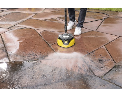 En person rengör gatsten med en Kärcher ytrengörare.