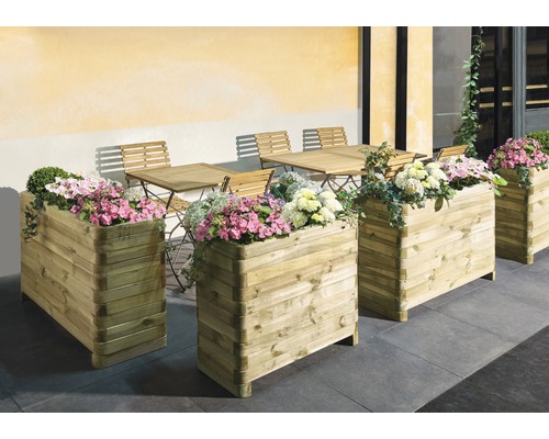 Flera trälådor med blommor på en terrass med bord och stolar.