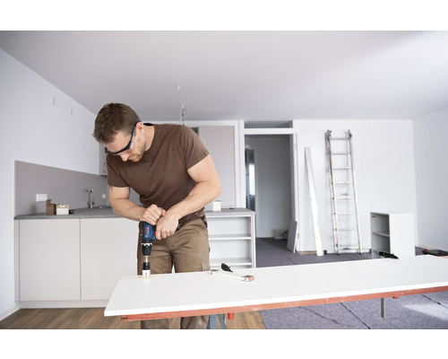 Man borrar hål i arbetsstycke med hålsåg i ljus lägenhet