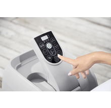 Kontrollpanel för en bärbar jacuzzi med digital display och olika funktionsknappar, som manövreras av en hand.