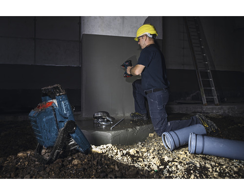 Hantverkare som arbetar med borrmaskin, byggstrålkastare och avloppsrör på en byggarbetsplats