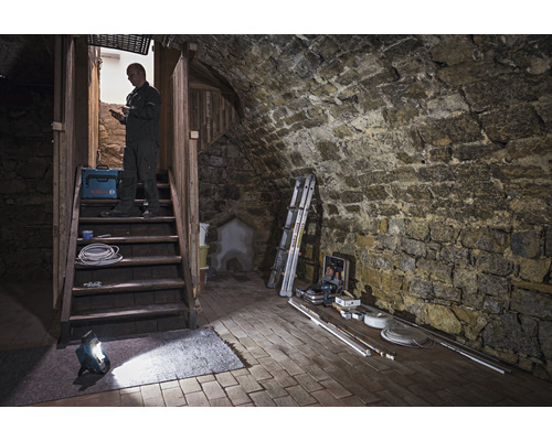 Källarutrymme med stentrappa, arbetslampa, verktygslåda och hantverkare