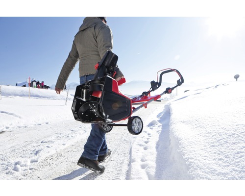 En person bär en snöslunga på en snöig väg.