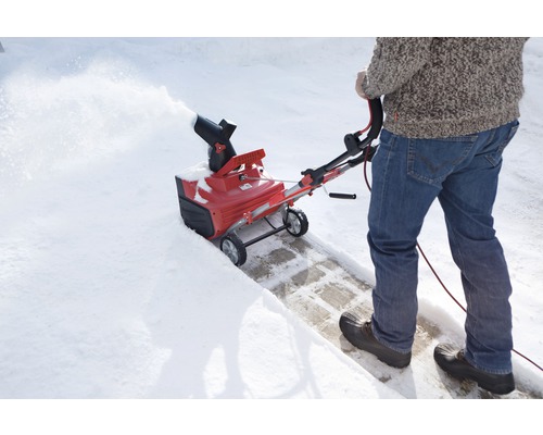 Person använder en snöslunga för att röja snö